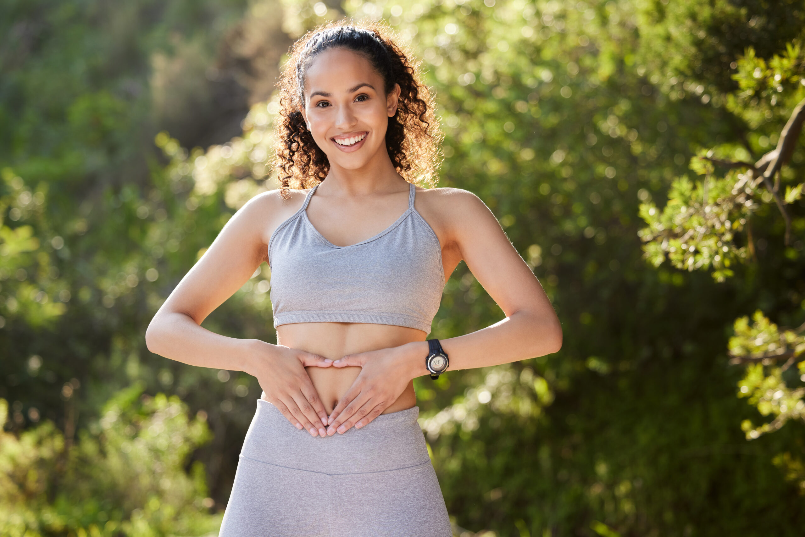 Shot of a young woman holding a heart on her tummy during a workout.